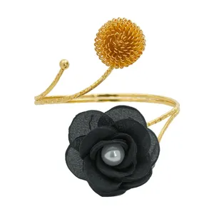 Goldenes verstellbares Metallarmband mit schwarzer Stoffblume, Perle und Goldkugel.