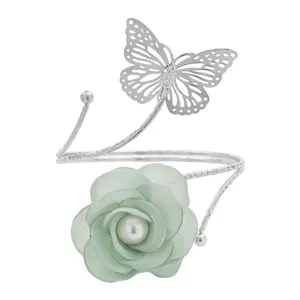 Bracciale da braccio in metallo argento con farfalla e fiore in tessuto verde chiaro.