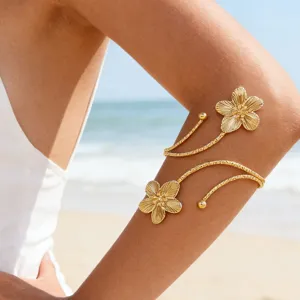 Primer plano detallado del brazalete de metal dorado con detalles florales en la playa.
