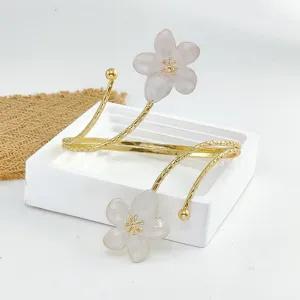 Primer plano detallado del brazalete abierto dorado con encantadores detalles de flores.