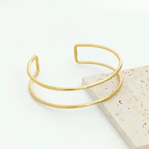 Detail view of a stylish gold double layer open cuff bracelet, chic geometric arm jewelry.