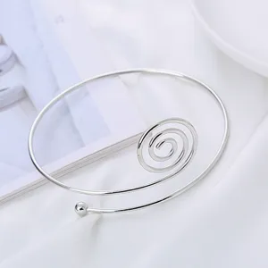 Primo piano di un bracciale da braccio aperto a spirale argentata minimalista, accessorio chic.