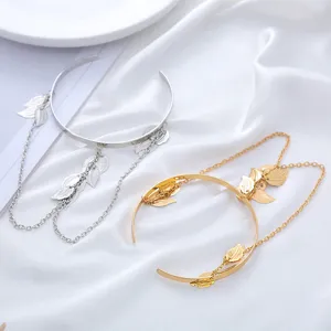 Primo piano dettaglio bracciale rigido foglia metallo elegante con catene, oro argento.