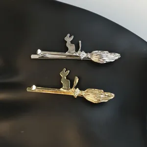 Close-up detail of cute cat and broom metal hair clips, silver and gold fashion side clips.