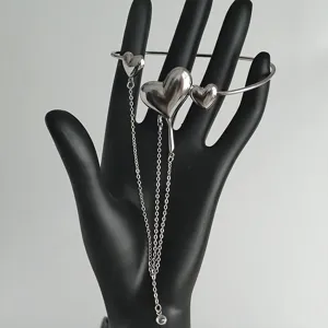 Primo piano dettagliato del bracciale rigido a cuore in metallo fuso argento con catene.