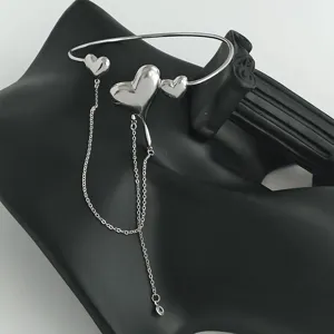 Dettaglio del bracciale da braccio a cuore in metallo lava con nappe a catena per donne.