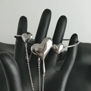 Dettaglio di un bracciale da braccio aperto a cuore in metallo fuso con nappe a catena delicate.