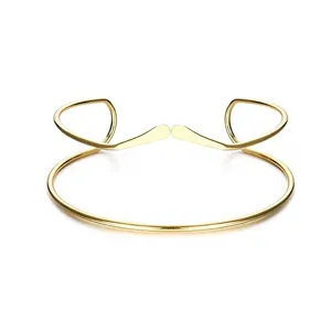 Primo piano dettagliato del bracciale da braccio geometrico dorato dal design aperto unico.