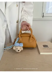 Minimalist Boston bag detail, casual yellow leather shell handbag with cute plush charm.