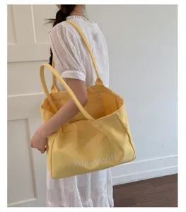 Detail of large yellow canvas tote bag, casual commuting shoulder bag with spacious capacity.