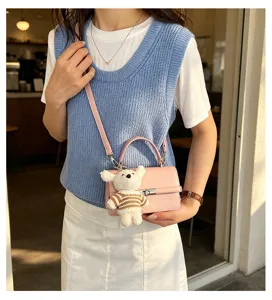 Pink leather handbag detailed view, stylish casual crossbody bag with cute bear pendant for women.