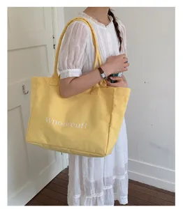 Detail view of large yellow canvas tote bag, casual shoulder design for daily commuting use.