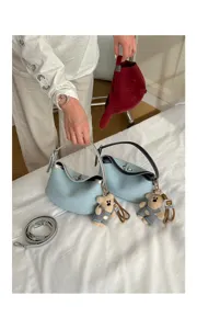 Stylish denim shoulder bag for women with metal turn-lock and cute bear pendant.