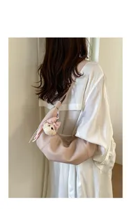 Detailed view of trendy croissant shoulder bag in soft leather with cute bear charm.