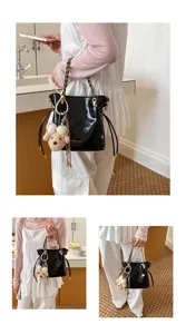 Detailed view of the stylish black patent leather shoulder bag featuring chic gold chain straps.