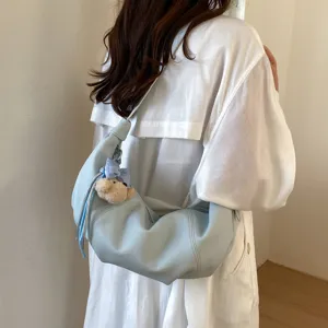Trendy light blue croissant shoulder bag with cute bear pendant for women daily commuting.