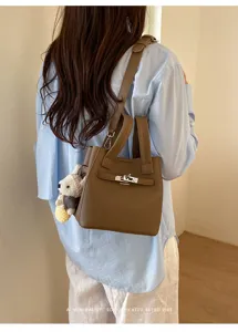 Brown litchi grain leather shoulder bag with cute bear pendant and metal turn lock detail.