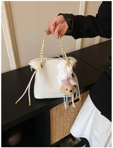 Chic white quilted bucket shoulder bag with cute puppy plush charm, stylish commute handbag.