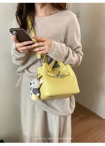 Yellow litchi pattern leather handbag, stylish shoulder crossbody bag with cute bear charm.