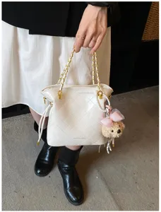 Detailed close-up view of the white quilted shoulder bag with chain strap and cute bear pendant.