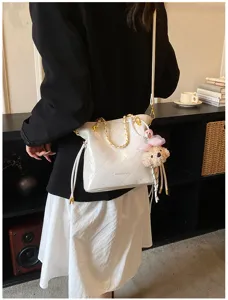 White quilted shoulder bag with gold chain strap, drawstring and cute bear pendant detail.