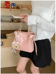 Chic pink quilted leather shoulder bag with golden chain and cute bear charm for daily fashion.