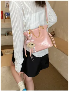 Stylish pink quilted shoulder bag with chain strap, cute teddy bear charm for women.