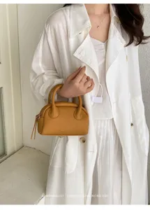 Detail view of a stylish minimalist Boston handbag in caramel leather for women daily wear.