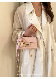 Close-up detail of a pink quilted chain shoulder bag with cute bear charm and twist lock.