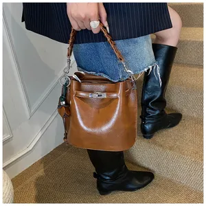 Retro brown bucket bag with woven handle and metal lock detail, stylish leather crossbody.
