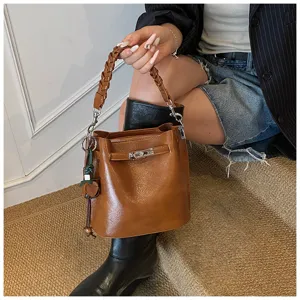 Retro brown leather bucket shoulder bag with braided handle and chic metal lock detail for women.