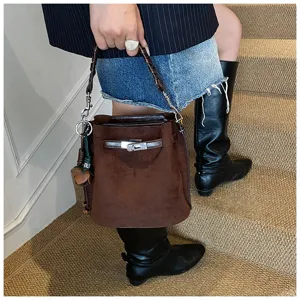 Detailed close-up of a brown suede bucket bag featuring metal lock clasp and braided handle.
