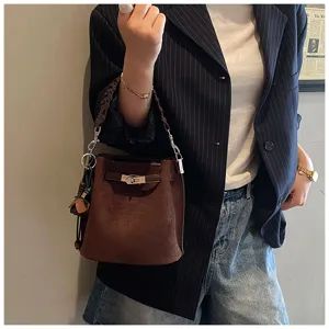 Retro brown bucket bag with metal lock detail and braided handle, stylish accessory.