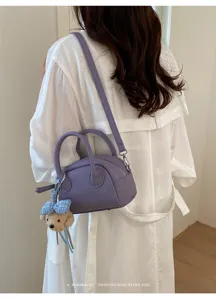 Detailed view of the stylish purple leather boston bag with a cute bear charm for women.