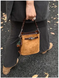 Retro brown suede bucket bag with braided top handle and metal twist lock design.