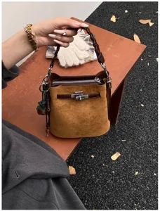 Brown suede bucket bag detail view with vintage turn-lock hardware and elegant braided handle.
