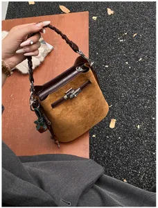 Vintage brown suede bucket bag with braided handle and metal lock detail for daily commuting.