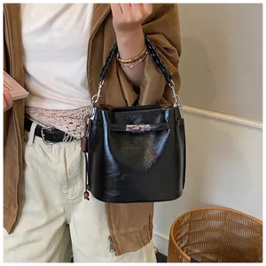 Retro black leather bucket bag with woven handle and metal turn lock for women daily use.