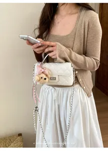 White quilted shoulder bag with chain strap and cute bear charm, elegant chic design for women.