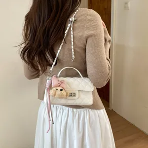 Chic quilted shoulder bag with chain strap, top handle, and cute plush bear charm.