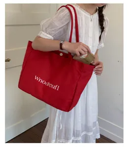 Detail view of a large capacity red canvas tote bag for women, minimalist daily commuter style.