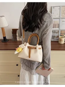 Detailed view of a chic beige bucket handbag with brown handles and a cute plush bear charm.