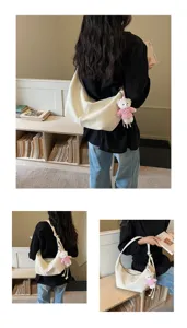 Detail shot showing slouchy white shoulder bag with cute bear charm worn by model in a room.