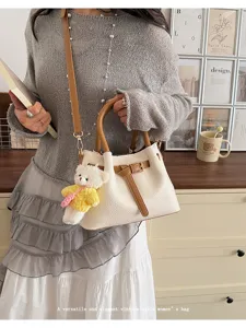 Detailed view of the stylish contrast color bucket bag with cute bear charm and shoulder strap.