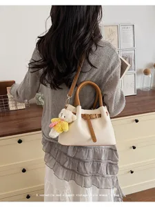 Detail view of a chic bucket shoulder bag with cute bear charm and contrast brown handles.
