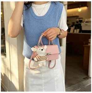 Close-up detail of pink leather mini handbag with cute white plush bear keychain and silver lock.