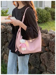 Chic pink hobo shoulder bag detailed shot, featuring premium texture and cute bear pendant.