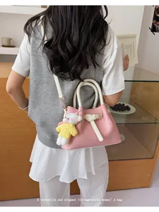 Detail view of the pink and white contrast shoulder handbag styled with a cute bear pendant.