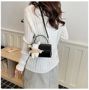 Stylish black retro shoulder cross-body small square bag for women with cute plush pendant detail.