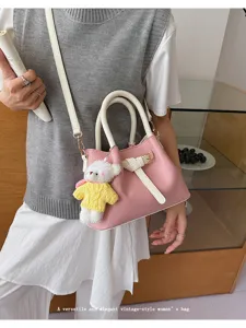 Chic pink and white contrast crossbody handbag with cute bear pendant for women style.